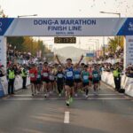 2026년 동아마라톤 피니쉬 라인을 통과하는 러너들과 지켜보는 관중들