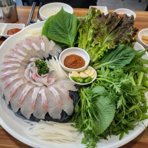 도다리회와 다양한 쌈 채소가 접시에 담겨 있는 모습