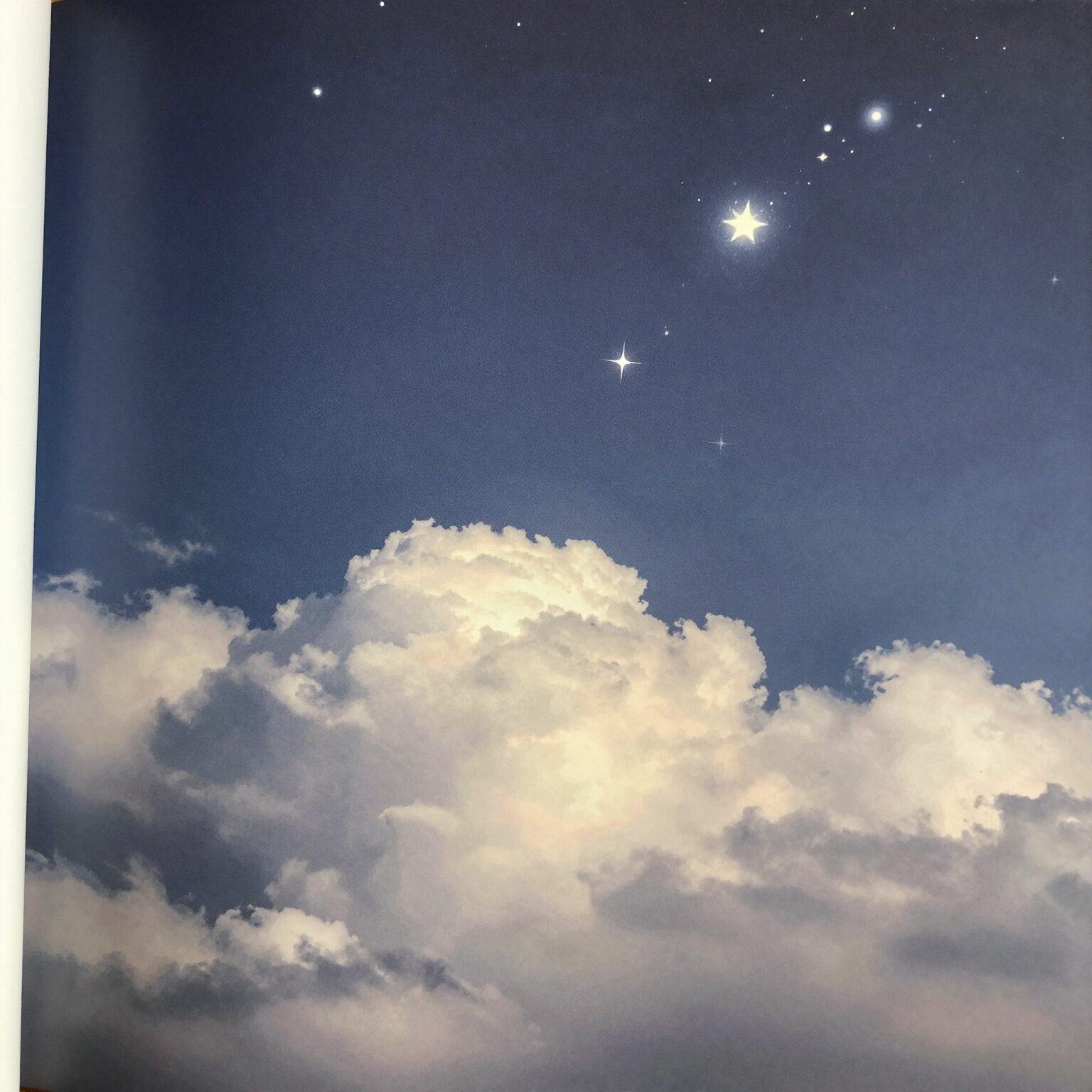 은유법 예시 그림으로 책 페이지 위에 떠오른 구름과 빛나는 별이 그려져 있음