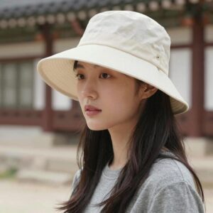 여성 모델이 챙이 긴 썬캡을 착용하고 야외에서 포즈를 취하고 있는 모습