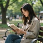 공원 벤치에서 시집을 읽는 손의 모습, 배경은 푸른 나무와 6월의 햇살