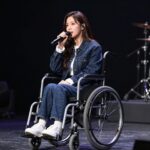 현대화 가수 감동의 비상 가수 현대화가 미스트롯 포유 무대에서 노래하고 있는 모습. 휠체어에 앉아 있지만 강한 눈빛으로 카메라를 응시하고 있다.