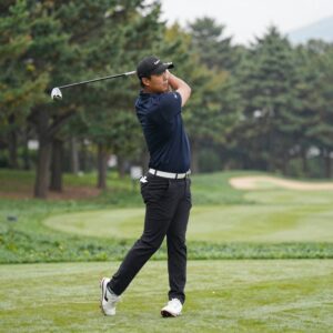 토요일 오후 강한 바람 속에서 프로 골퍼가 아이언 샷을 준비하는 모습, 골프 무빙데이의 치열한 경쟁을 상징