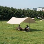 여름 캠핑장 잔디밭에 설치된 대형 그늘막 천막 모습