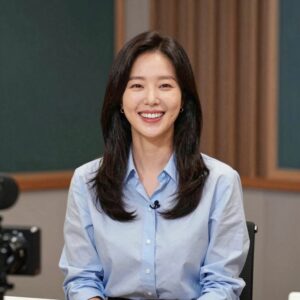 엄지인 아나운서가 KBS 스튜디오에서 진행하고 있는 모습. 화사한 블라우스를 입고 환하게 웃고 있다.