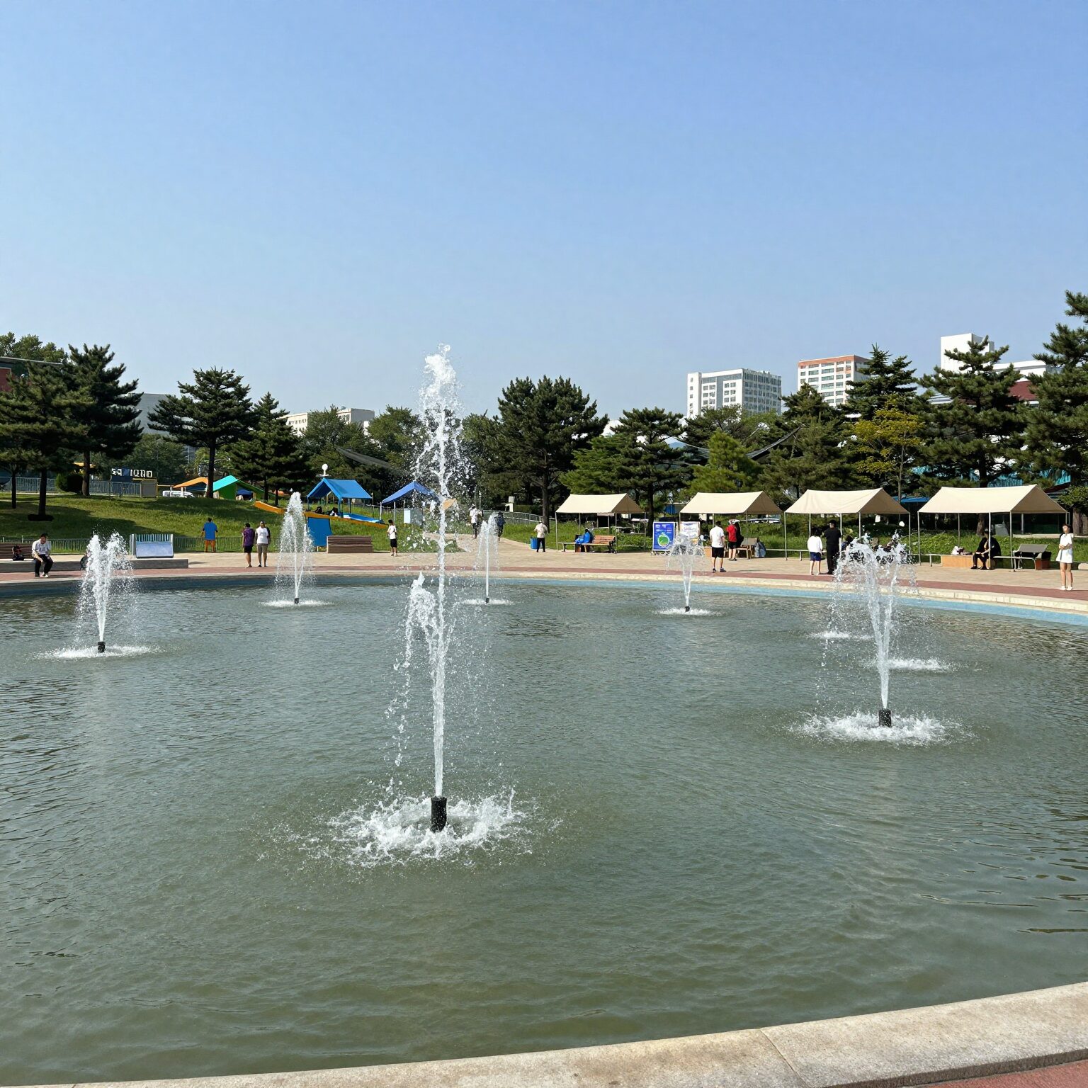 부천 중앙공원 물놀이장 전경. 얕은 물과 분수, 평상, 그늘막이 보인다.