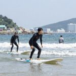 강릉 서핑 명소 사천해변에서 초보자들이 서핑 보드 위에 서 있는 모습