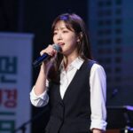 투개월 김예림 음악 이야기 투개월 김예림이 무대에서 마이크를 잡고 노래하는 모습, 배경은 어두운 조명과 블루톤 조명